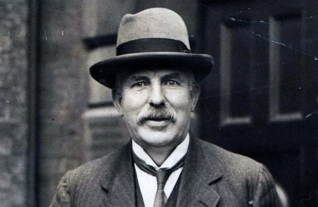 Ernest Rutherford con sombrero y traje, en una fotografía en blanco y negro.