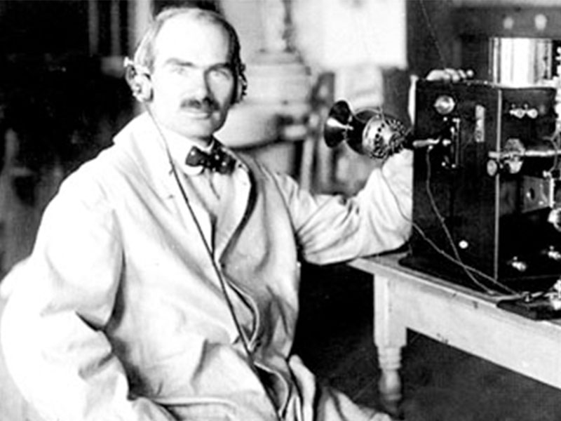 Lee de Forest, ingeniero eléctrico e inventor del triodo, sentado en su laboratorio junto a un equipo de radio experimental.