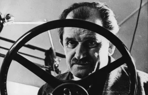 Retrato en blanco y negro de Ferdinand Porsche, ingeniero automovilístico, visto a través del volante de un automóvil, reconocido por ser el creador del Volkswagen Tipo 1, conocido como 'Escarabajo"