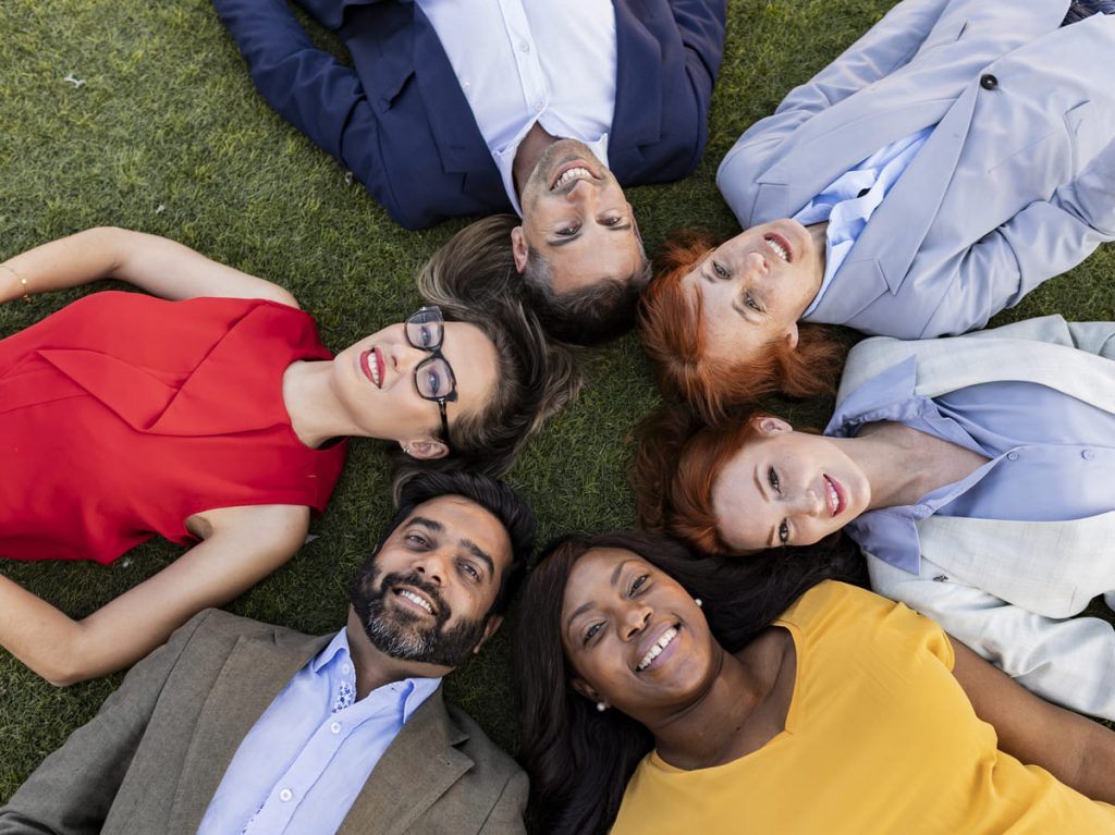 Equipo multirracial tumbados en círculo en cesped