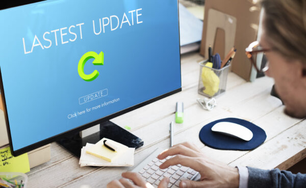 Persona trabajando en un ordenador de escritorio mientras en la pantalla aparece el mensaje “Lastest Update” con un botón de actualización.