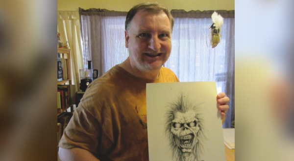 Derek Riggs mostrando un dibujo a lápiz de Eddie the Head, la icónica mascota de Iron Maiden, en su estudio.