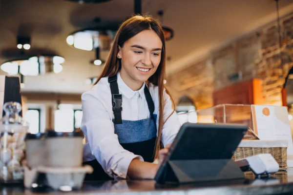 Barista utilizando una tablet para gestionar pedidos en una cafetería.