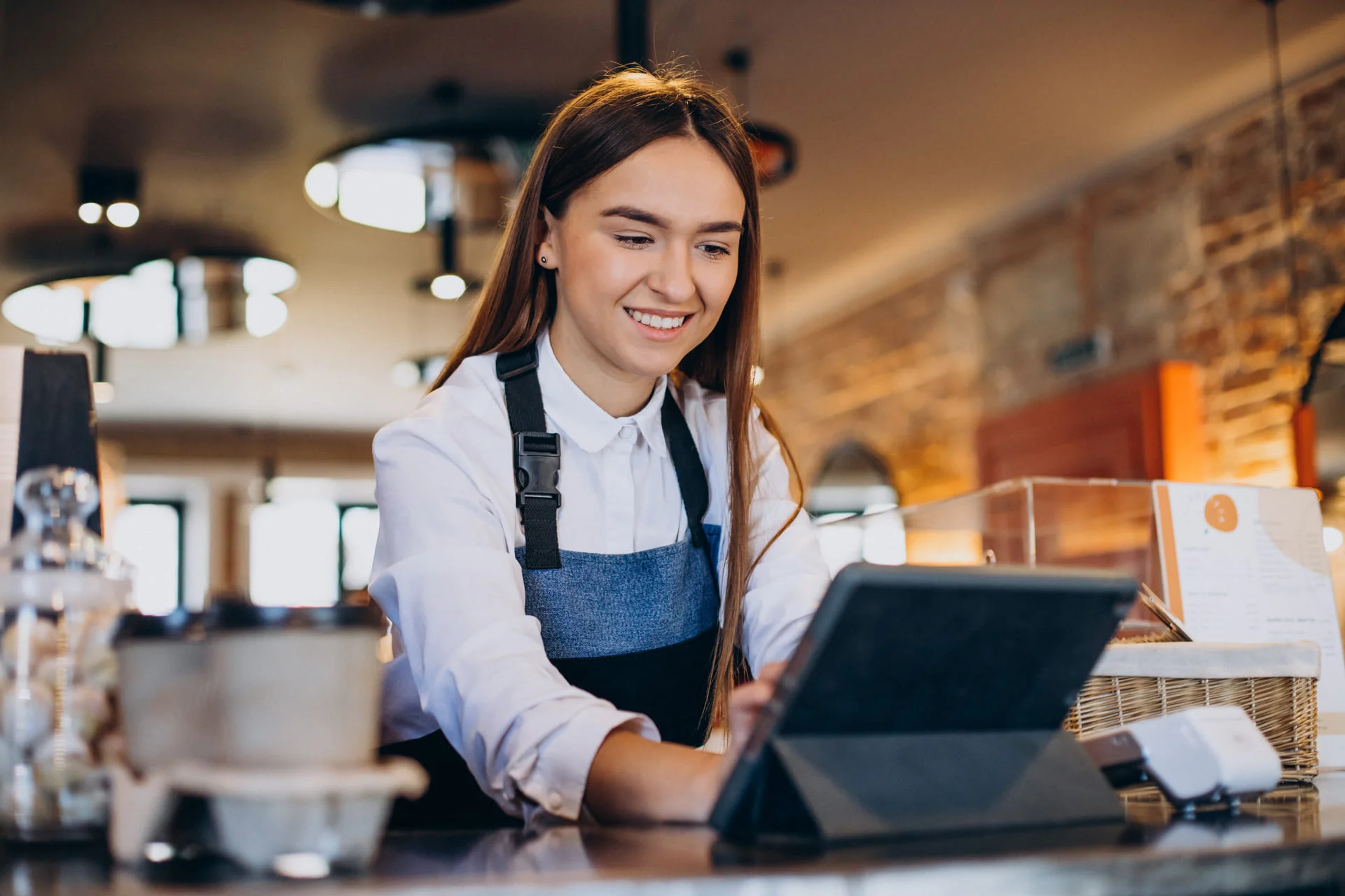 Barista utilizando una tablet para gestionar pedidos en una cafetería.