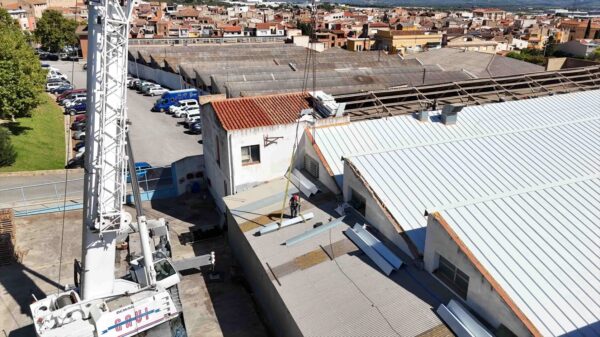 Instalación de cubierta metálica en una nave industrial con ayuda de una grúa.