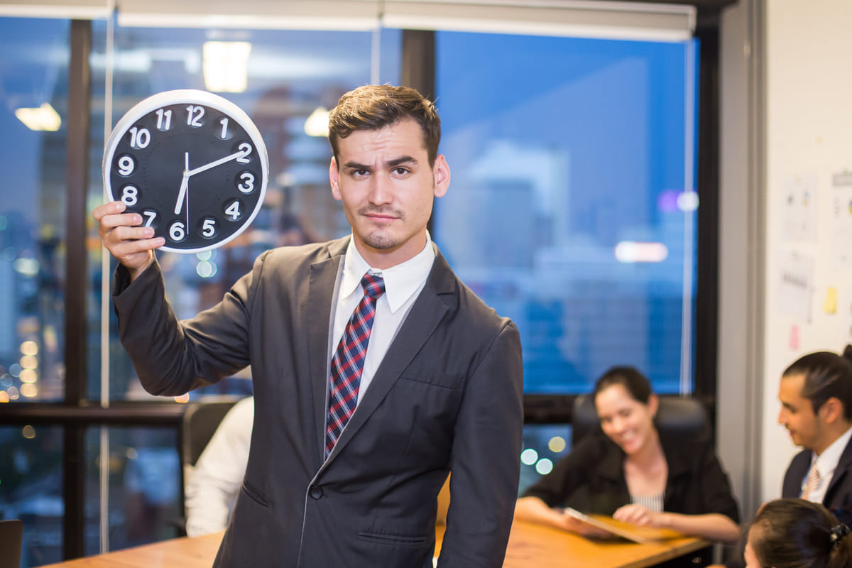 Hombre de negocios sujetando un reloj de oficina