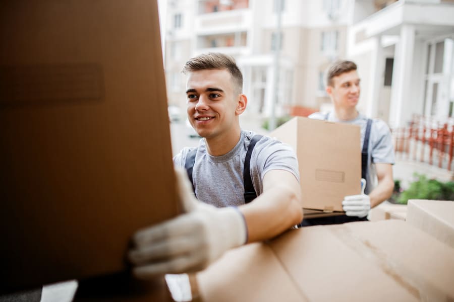 Operarios de una empresa de mudanzas cargando cajas de cartón durante el traslado de un edificio residencial.
