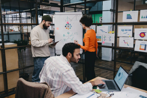 Equipo de trabajo compartiendo ideas con una pizarra, una tableta y un ordenador en una oficina