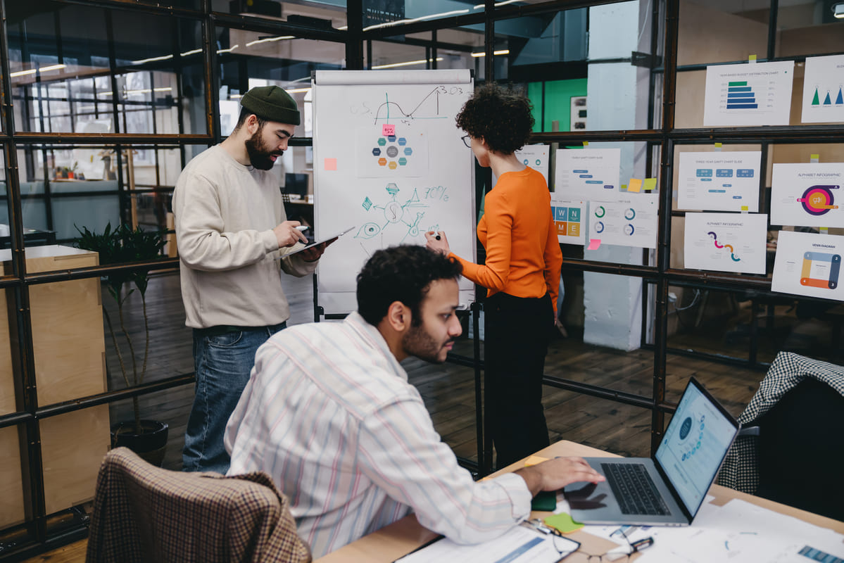 Equipo de trabajo compartiendo ideas con una pizarra, una tableta y un ordenador en una oficina